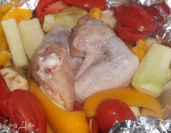 Сковороду или форму застелить фольгой. Уложить овощи. В середину выложить крылья.