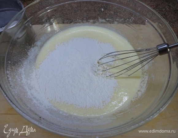 Влить ряженку и всыпать соду. Небольшими порциями начинаем просеивать муку, после каждой порции тщательно перемешиваем венчиком, чтобы не образовалось комочков. Тесто должно быть похоже на густую сметану. Включаем чайник.