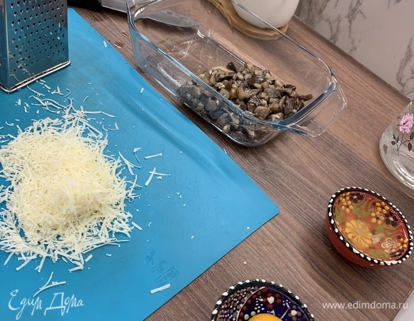 Выложить грибы в форму, разровнять по дну. У меня великовата форма — сначала пыталась заполнить ее не на всю длину, но тщетно) Так что смело можно было разравнивать сразу. Натереть сыр — тут по вкусу: можно добавлять больше, тогда получится именно запеканка, можно меньше — будет более похоже на пюре. Отделить желтки от белков.