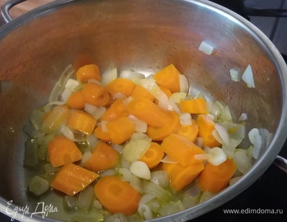 На разогретом оливковом масле пассеровать нарезанные лук и чеснок до прозрачности, добавить нарезанную морковь и обжарить в течение нескольких минут.