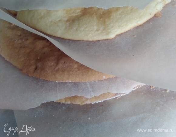 Готовые коржи складывать стопкой, проложив бумагой для выпечки. Обрезки коржей испечь и измельчить до крошки.