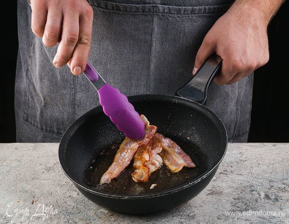 Бекон нарежьте тонкими пластинами и обжарьте на сковороде до золотистой корочки.<br />
 