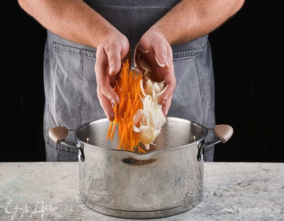 В разогретую кастрюлю налейте масло, добавьте лук и морковь, обжарьте 5 минут.