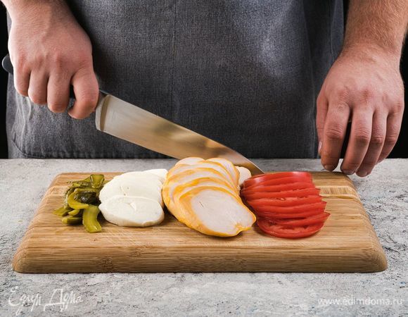Копченую куриную грудку наредьте пластинами. Огурцы нарежьте слайсами, моцареллу и помидор нарежьте кружочками.