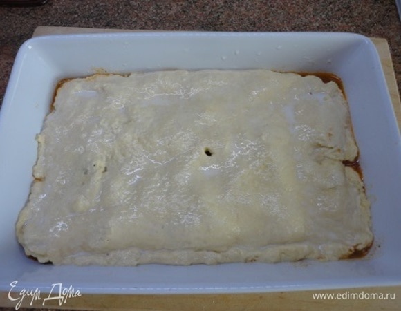 Раскатайте тесто в прямоугольник по размеру формы для запекания и накройте им курицу с овощами, подворачивая края вниз. Смажьте верх молоком.