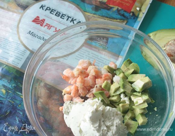 Отложите количество креветок по количеству кексов (например, у меня получается 10 кексов, и 10 креветок я откладываю). Остальные креветки отварите и очистите от панцирей. Спелое авокадо нарежьте небольшими кубиками (можно измельчить до состояния пюре), смешайте с нарезанными креветками и творожным сыром. У меня сыр изначально с зеленью и травами. На этом этапе уходит примерно 150–200 г из указанного количества сыра.