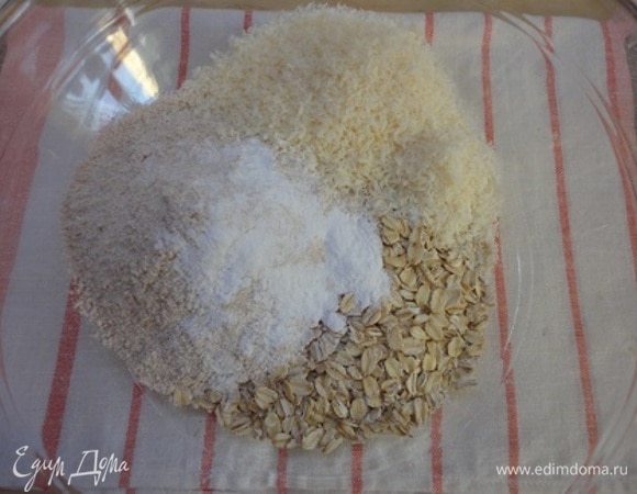 Включите духовку для разогрева на 180°C. Смешайте муку, хлопья, разрыхлитель, соль, кокосовую стружку. Перемешайте.