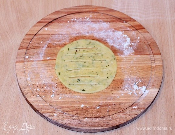 На припыленной мукой разделочной доске формируем из шариков теста круглые лепешки диаметром 10 см. Надрезаем ножиком на лепешке полоски.