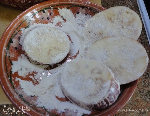 Включить духовку на разогрев до 200°C. В сковороде разогреть масло для жарки, а баклажаны перед жаркой обвалять в муке.