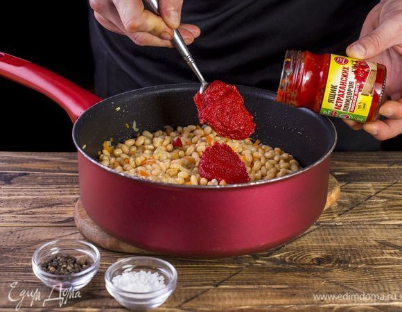 Добавьте фасоль и томатную пасту ТМ «Ящик астраханских помидоров. Посолите и поперчите. Тушите под крышкой до готовности фасоли, добавляя необходимое количество воды.