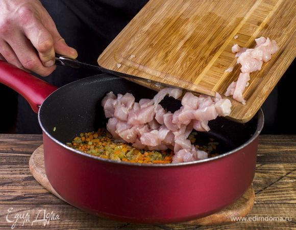 В глубокой сковороде обжарьте до мягкости лук и морковь. Добавьте к ним куриное филе и тушите пять минут.