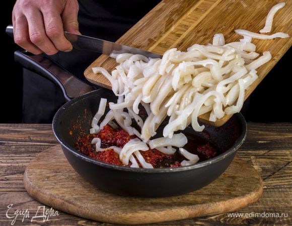 Кальмары разморозьте, очистите, нарежьте тонкой соломкой и припустите на сковороде с томатной пастой и луком.