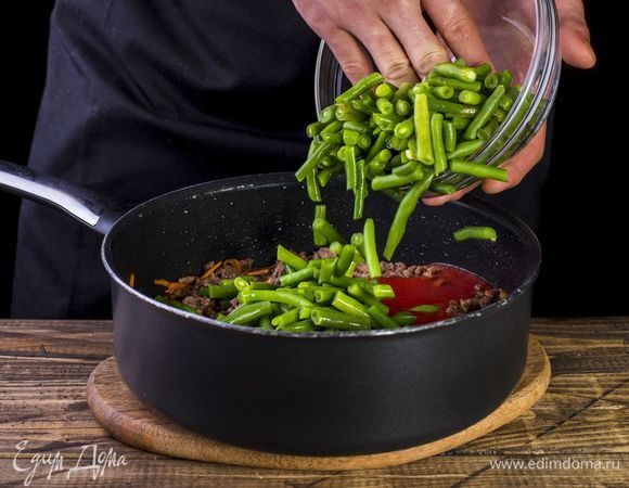 Добавляем в сковороду стручковую фасоль, немного воды и тушим.