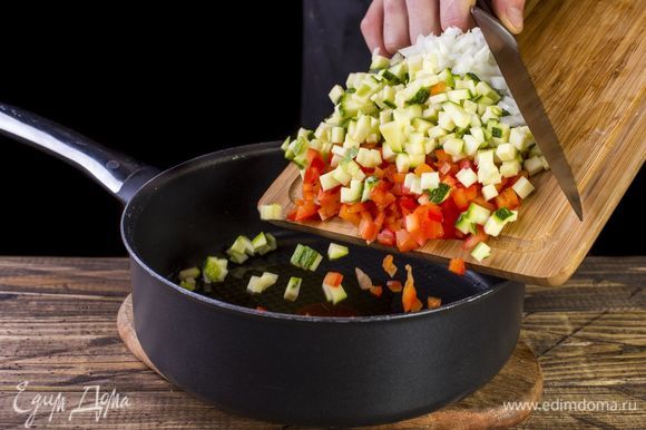 Налейте в сковороду растительное масло, добавьте овощи. Потушите две минуты.