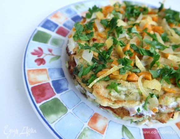 Чередовать слои. На верхний кабачковый блин поместить морковь с луком, измельченную зелень, кусочки цедры, снятой с лимона с помощью ножа для чистки овощей.