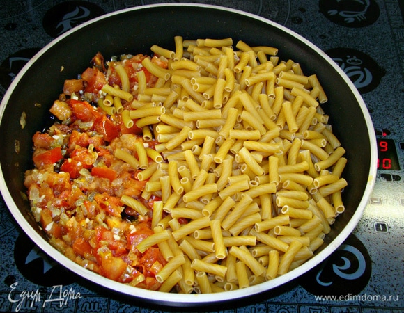 К обжаренным овощам всыпать пачку макарон (450–500 г), посолить и поперчить по вкусу.