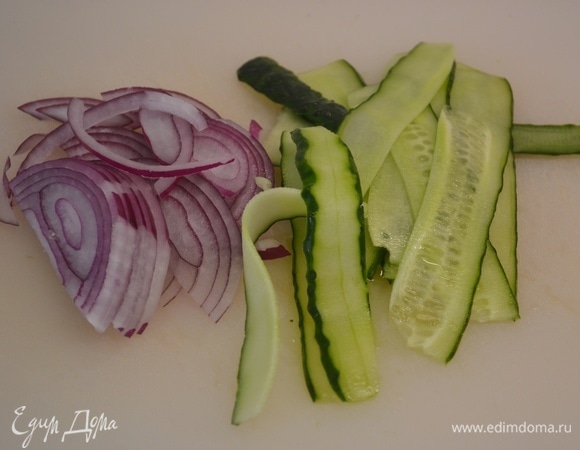 Булочки для бургеров разрезать и подсушить на сковороде. Красный лук нарезать тоненькими полукольцами, огурец нарезать на слайсы.