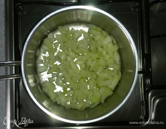 В кастрюлю с толстым дном добавляем оливковое масло и выкладываем нарезанный лук. Затем ставим кастрюлю на минимальный огонь большой конфорки плиты. Обжариваем лук, постоянно помешивая, около 3 минут.