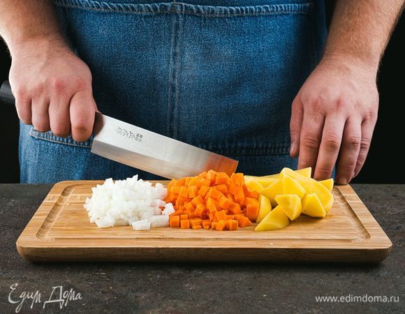 Налейте воду в кастрюлю, дождитесь, когда вода закипит. Почистите лук, морковь и картофель. Мелко нарежьте лук, морковь порубите маленькими кубиками, картофель нарежьте небольшими кубиками.