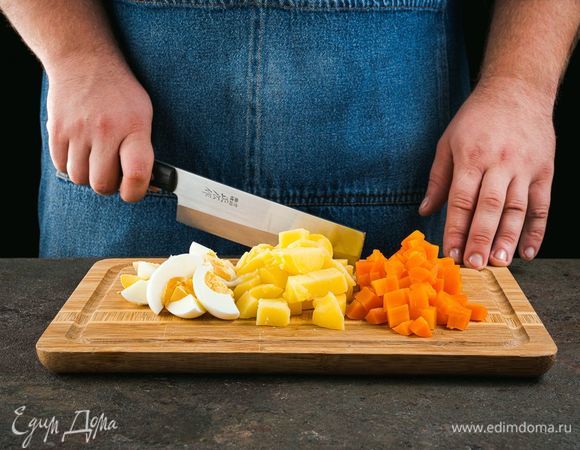 Отварите картофель, морковь и яйца. Нарежьте яйца дольками, овощи — кубиками.