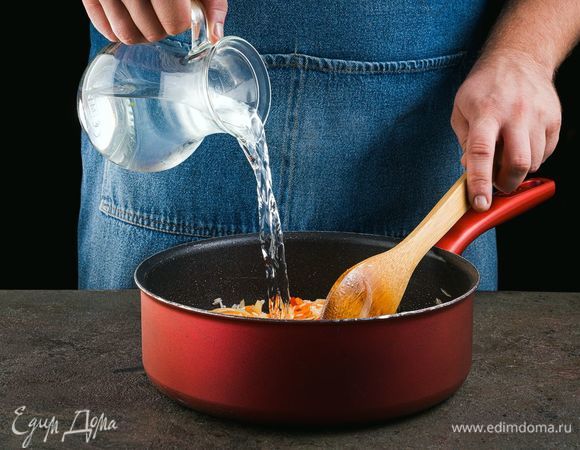 Затем налейте в сотейник воды. Перемешайте и закройте крышкой. После закипания воды посолите и поперчите. Тушите рис до готовности, помешивая, и добавляя при необходимости воду. 