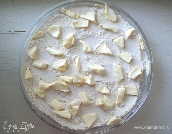 На творог высыпать оставшуюся сухую смесь. На нее выложить 70 г сливочного масла, нарезав его маленькими кусочками.