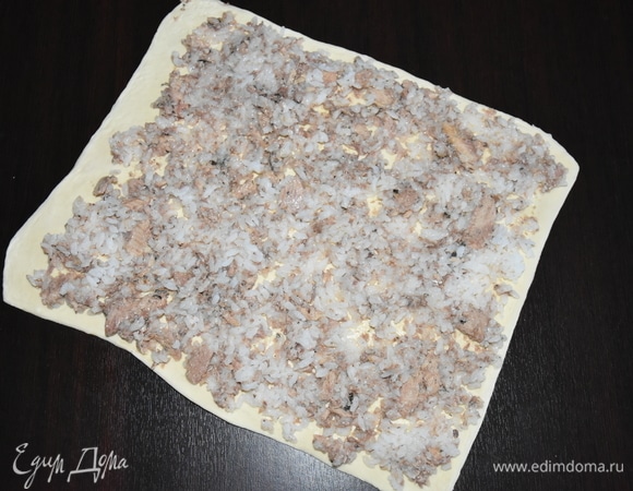 Слоеное тесто раскатать в одном направлении в прямоугольник. Распределить по всему периметру теста начинку с рыбой.