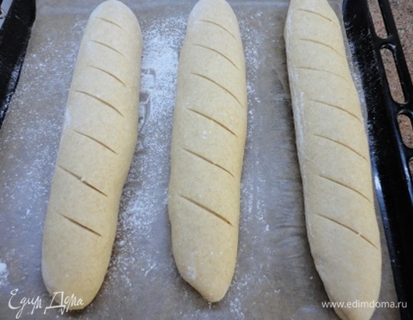 Выкладываем на противень, выстланный бумагой и посыпанный мукой. Подошедшие багеты надрезаем и включаем духовку на разогрев до 220°C.