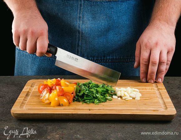 Чеснок мелко нарежьте, помидоры разрежьте пополам.