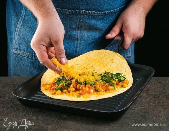 Выложите на одну половинку лепешки обжаренные овощи с креветками, мелко нарезанную петрушку. Сверху посыпьте тертым сыром.