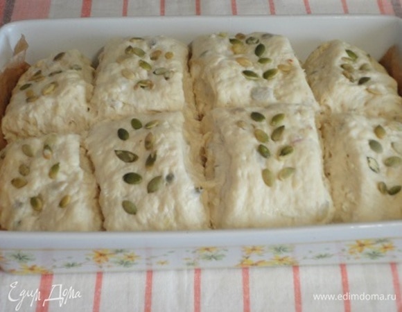 Включите духовку на разогрев до 220°C. Подошедшее тесто смажьте водой и посыпьте оставшимися тыквенными семечками. Выпекайте 10 минут с горячей водой, потом убавьте температуру до 200°C и выпекайте еще 25–30 минут до готовности.