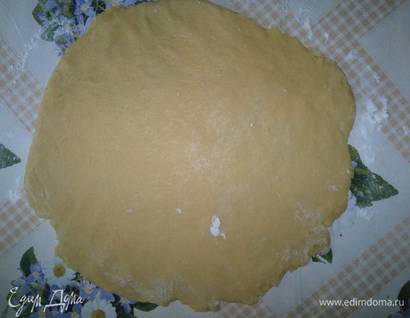 Достать тесто из холодильника. Разделить в соотношении 1:2. Большую часть теста раскатать на посыпанном мукой столе в круг, диаметром равный диаметру формы для запекания плюс бортики 4–5 см.