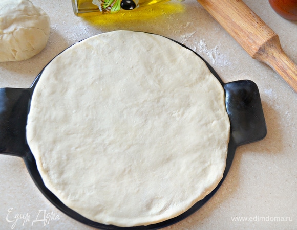 Духовку включите на 210–220°C. Форму для пиццы немного смажьте оливковым маслом (я использую специальную форму для пиццы, d=26 см) и выложите на нее половину теста (у нас будет 2 пиццы), слегка обмять и придать форму круга. Накройте полотенцем и отставьте на 10 минут. Затем тесто необходимо смазать оливковым маслом.