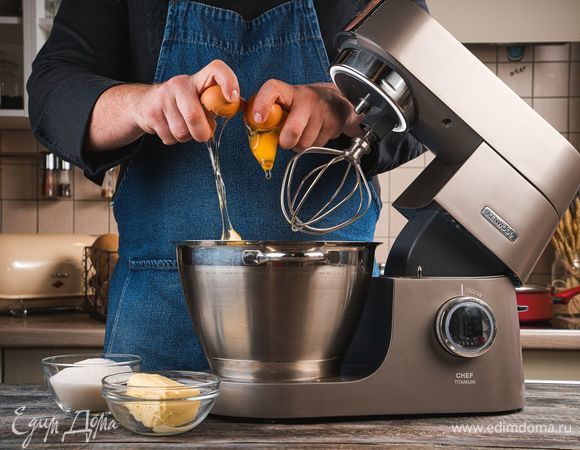 Установите на кухонную машину KENWOOD насадку-венчик для взбивания. Положите в чашу размягченное сливочное масло, сахар и начинайте добавлять по одному яйца. Взбивайте массу после добавления каждого яйца.