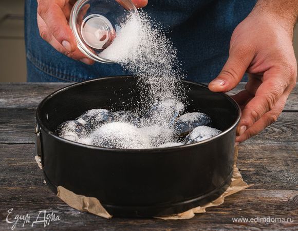 Форму для выпекания смажьте сливочным маслом, выложите ровным слоем сливы и посыпьте сахаром.