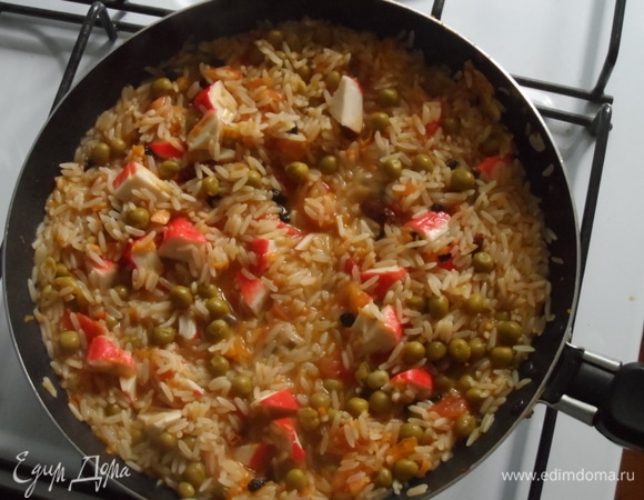 Добавить нарезанные крабовые палочки. Перемешать. После этого разровнять по сковороде и оставить готовиться, не помешивая. Когда вода выпарится, она будет даже немного потрескивать. Готово будет, когда на краях сковороды появится зажаренная корочка.