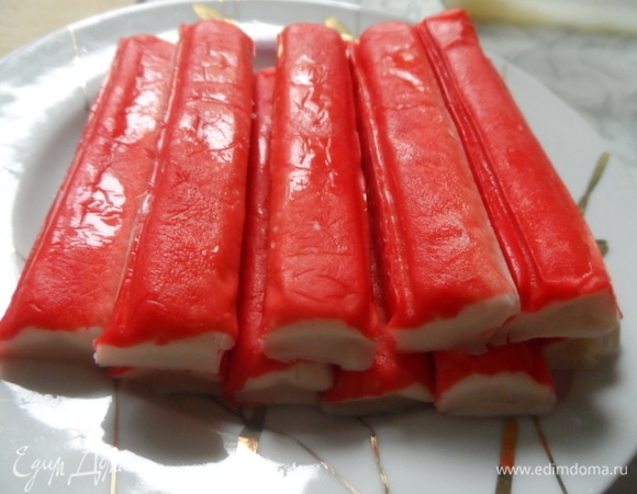 Рис отварить, промыть, откинуть на дуршлаг. Крабовые палочки нарезать поперек ломтиками.