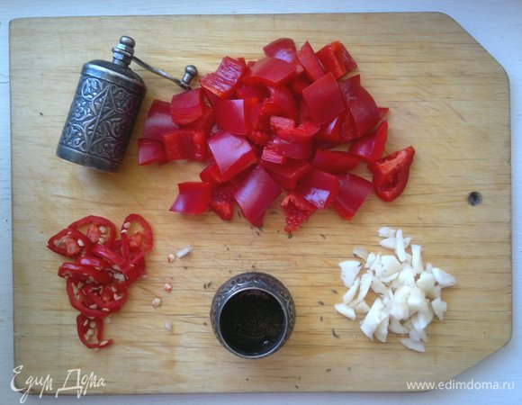 Сладкий перец помыть, обсушить, очистить от семян и перегородок, нарезать крупными кубиками. Красный острый перец нарезать колечками. Чеснок почистить, размять ножом, мелко нарезать. Если тмин в семенах, то смолоть его в мельничке.