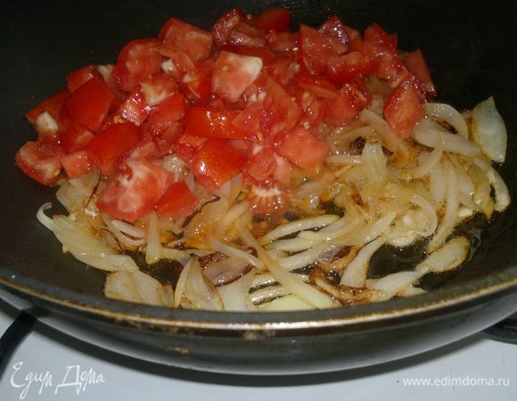 К обжаренному луку добавить кубики помидоров, перемешать.
