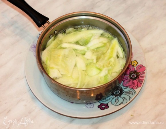 Второй кабачок тонко нарезать при помощи овощерезки и отварить в подсоленной воде до полуготовности. Затем отварить до полуготовности 6 пластин кабачка. Воду слить через сито.