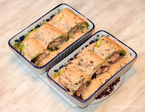 Полить кабачковые рулеты сверху соусом и отправить в разогретую до 180°C духовку на 30 минут. Затем кладем на рулетики пластины сыра и половинки помидорчиков черри, посыпаем обжаренным кунжутом. Ставим формочки в духовку до расплавления сыра на 1–2 минуты.