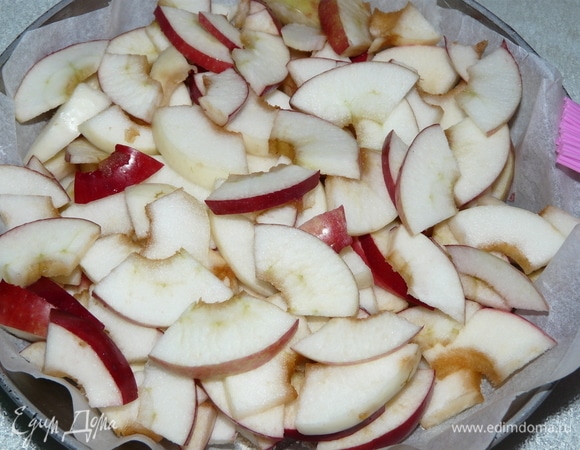 Нарезаем яблоки сначала дольками, а потом — кусочками. Заранее приготовим форму: смазываем растительным маслом и дно посыпаем панировочными сухарями. Я положила пергамент между формой и пирогом. Далее выкладываем нарезанные яблоки. И отодвигаем в сторону.