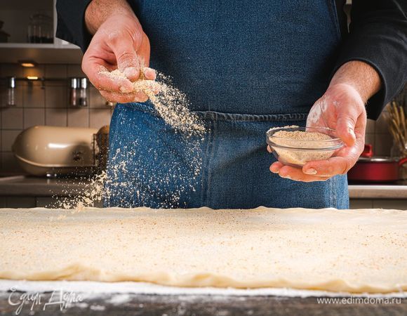 Смажьте тесто растопленным сливочным маслом, посыпьте панировочными сухарями.