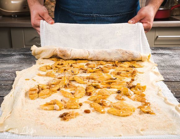 Выложите начинку на тесто равномерным слоем и с помощью полотенца сверните рулет.