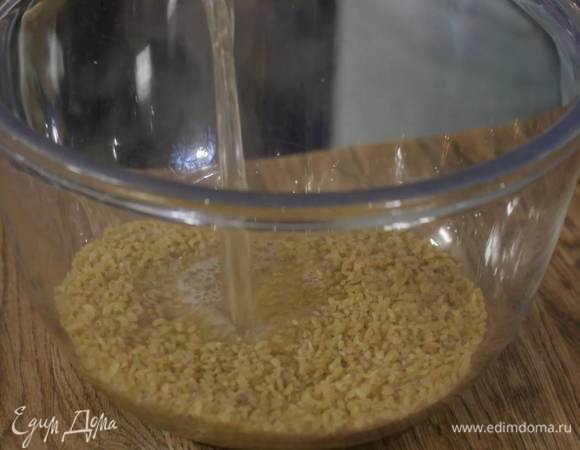 Булгур всыпать в глубокую посуду, залить 250 мл кипятка, затянуть пищевой пленкой и дать жидкости впитаться.