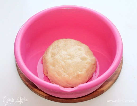 Собираем тесто в ком. Смазываем миску растительным маслом (1 ч. л.) и выкладываем тесто. Прокручиваем тесто в масле. Накрываем миску пленкой, чтобы тесто не обветрилось.