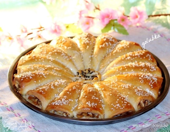 Затем переключаю духовку на 180°C, достаю пирог и смазываю яичным желтком (1 шт.), смешанным с молоком (1 ст. л.). Посыпаю пирог обжаренным на сухой сковороде кунжутом.