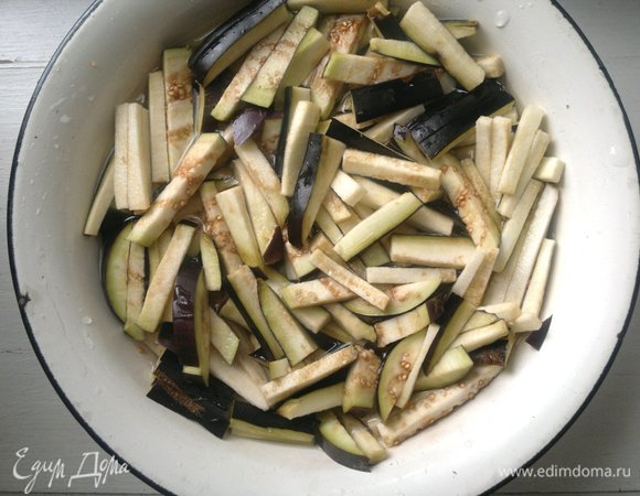 Сложить баклажаны в миску, посыпать солью (1 ст. л.), залить водой. Оставить на полчаса.