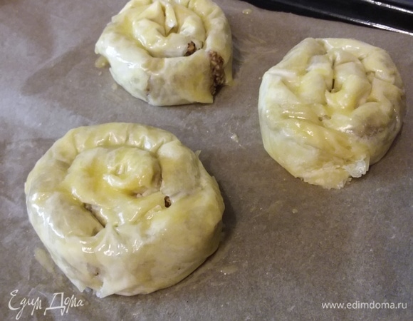 Если листы тонкие, то на каждую улитку пойдет по 2 листа. Первый нужно смазать маслом, выложить второй, смазать маслом и выложить начинку. Скатать в рулет, рулет свернуть в улитку. Когда все заготовки будут лежать на противне, их нужно смазать маслом и запекать в заранее разогретой до 180°C духовке 30 минут.