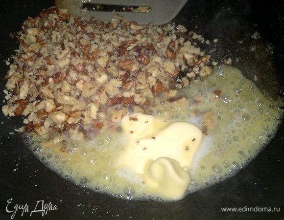 В растопленный сахар выложить сливочное масло, всыпать орехи. Готовить 2–3 минуты, помешивая.